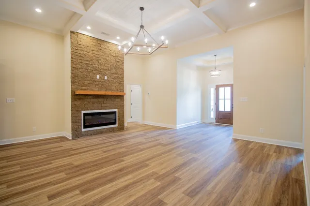 a view of a livingroom with a fireplace wooden floor and chandelier