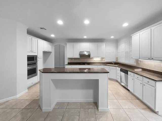 a kitchen with stainless steel appliances granite countertop a stove top oven a sink and a refrigerator