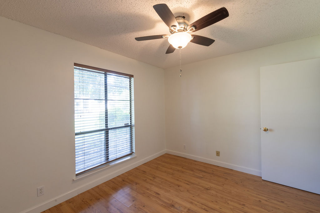 5310 Presidio Road Austin, TX 78745 - Photo 26 of 34 A well-lit bedroom features durable laminate flooring and a functional ceiling fan with lighting.