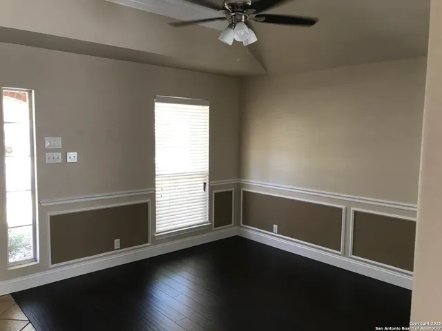 an empty room with wooden floor fan and windows