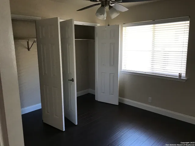 a view of empty room with wooden floor and fan