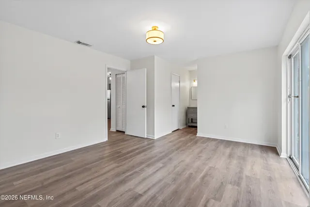 a view of an empty room with wooden floor and window