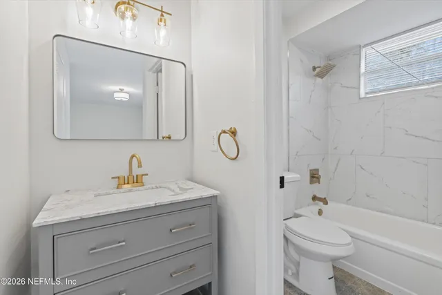 a bathroom with a toilet sink vanity tub and mirror