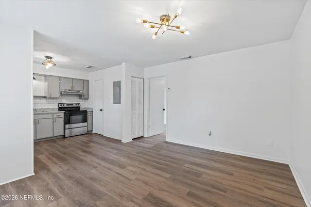 a view of kitchen with wooden floor electronic appliances and cabinets