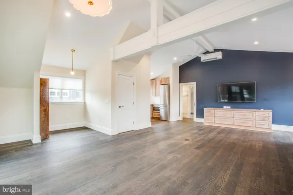 a view of an empty room with window and wooden floor