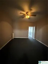 a view of an empty room and chandelier fan