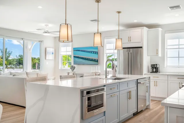 a kitchen with stainless steel appliances a sink a stove a refrigerator a center island and windows