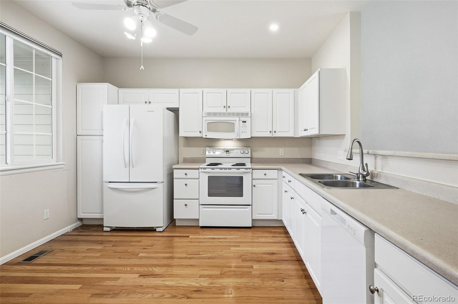 2526 South Tucson Circle Aurora, CO 80014 - Photo 15 of 33 a kitchen with granite countertop a white refrigerator oven a sink dishwasher and white cabinets with wooden floor