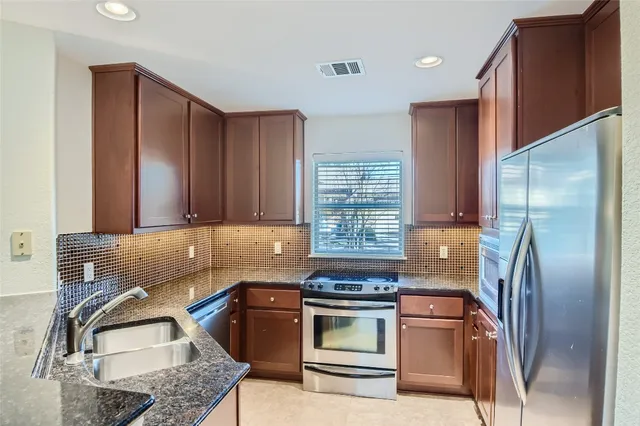 a kitchen with stainless steel appliances granite countertop a refrigerator sink and stove