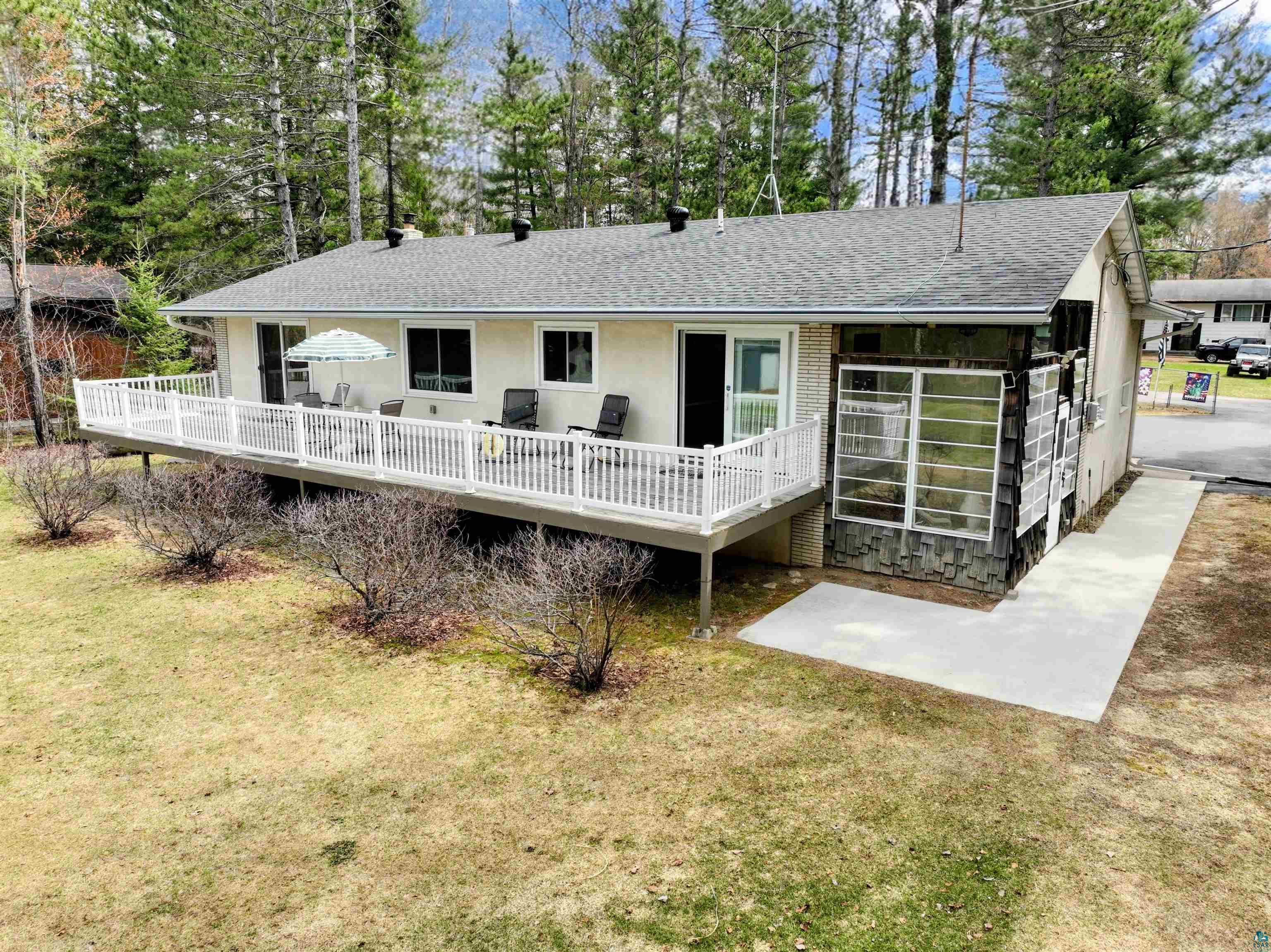 3975 Long Lake Shores Road Eveleth, MN 55734 - Photo 62 of 84 Exterior featuring a spacious elevated deck with white railing, multiple large windows, and an enclosed sunroom with stone veneer accents
