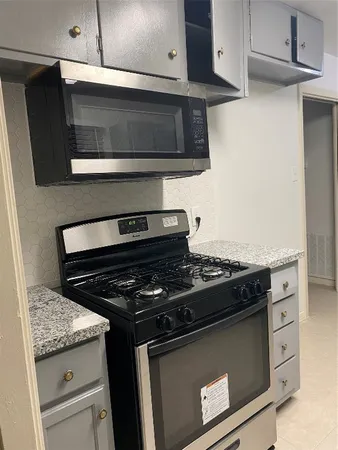 a kitchen with granite countertop a sink and a white cabinets