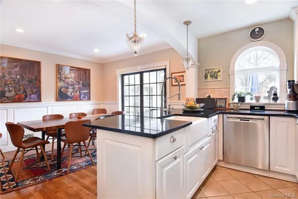 a kitchen with stainless steel appliances granite countertop a stove a sink dishwasher and white cabinets with wooden floor