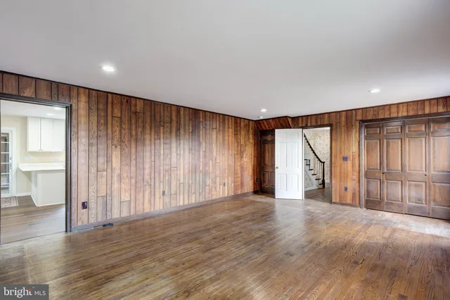 a view of an empty room with wooden floor and windows