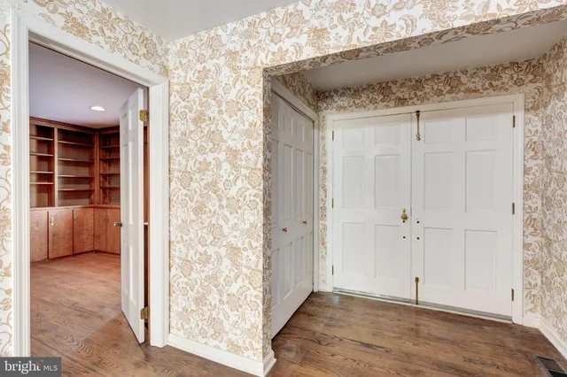 a kitchen with stainless steel appliances a stove a refrigerator a sink and white cabinets with wooden floor