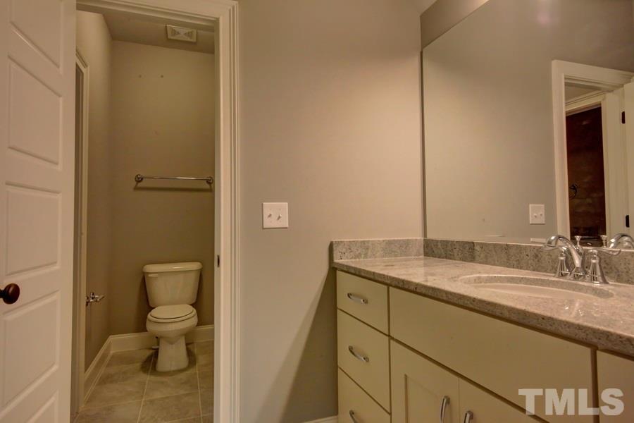6909 Old Mills Road Fuquay-Varina, NC 27526 - Photo 20 of 25 a bathroom with a granite countertop sink toilet and shower