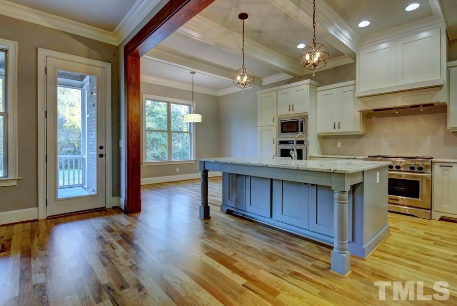 6909 Old Mills Road Fuquay-Varina, NC 27526 - Photo 5 of 25 a kitchen with stainless steel appliances granite countertop wooden floors and view of living room