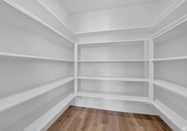 1002 West Temple Rim Lane Payson, UT 84651 - Photo 23 of 68 Walk-in pantry featuring expansive shelving, white painted walls, white baseboards, and wood-finish flooring