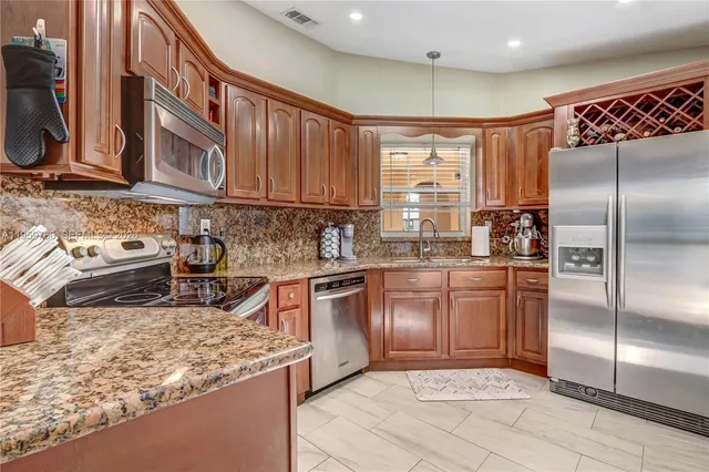 a kitchen with stainless steel appliances granite countertop a refrigerator sink and stove