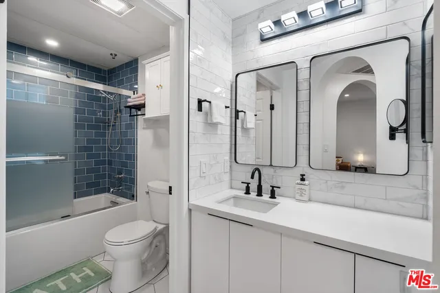 a bathroom with a double vanity sink toilet mirror and shower
