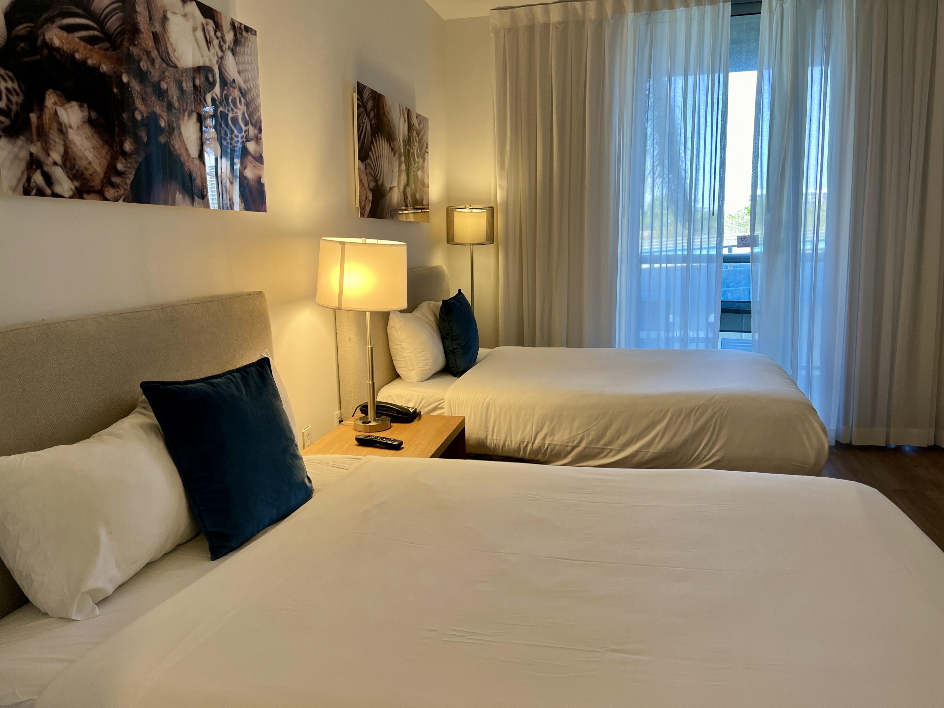 2602 East Hallandale Beach Boulevard, Unit R308 Hallandale Beach, FL 33009 - Photo 20 of 74 a bedroom with two beds and lamp on desk