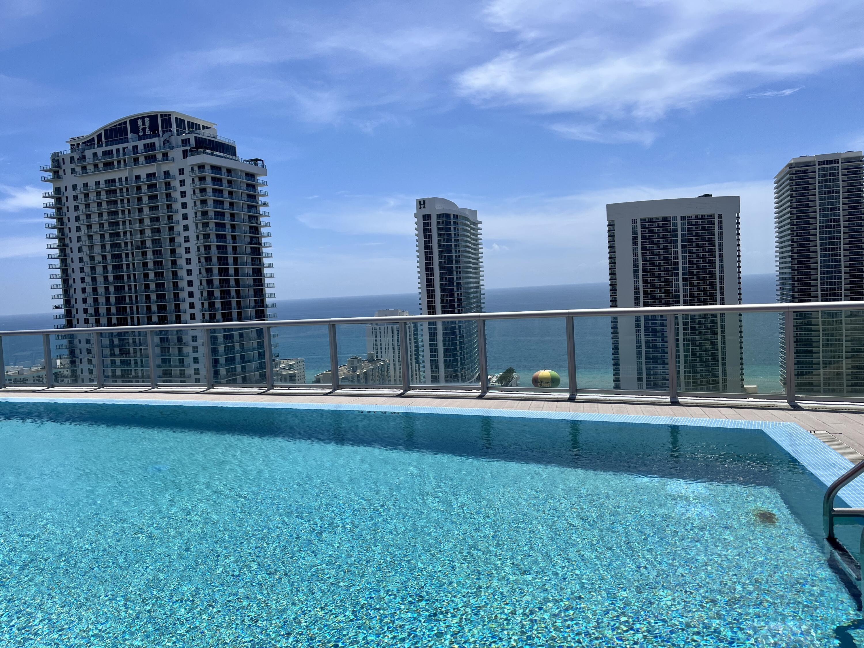 2602 East Hallandale Beach Boulevard, Unit R308 Hallandale Beach, FL 33009 - Photo 35 of 74 a view of a large building with a big yard and large trees