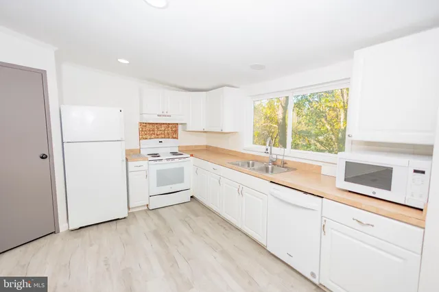 a kitchen with granite countertop white cabinets and white appliances