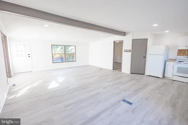 a view of empty room with wooden floor and window