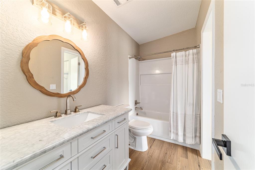 6155 Southeast Stetson Road Belleview, FL 34420 - Photo 30 of 68 a bathroom with a granite countertop toilet a sink and a mirror