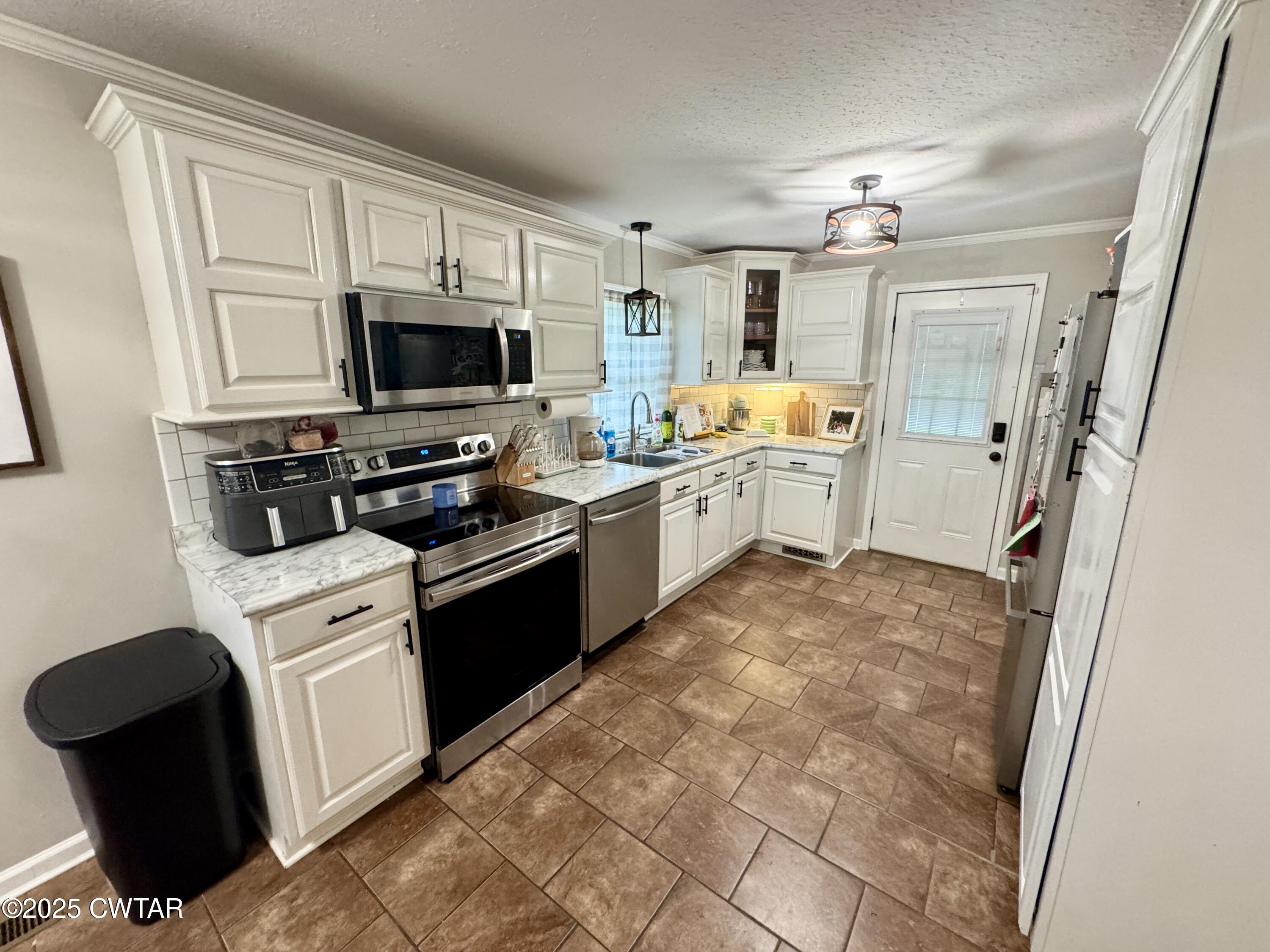 302 Flora Circle Newbern, TN 38059 - Photo 8 of 20 a large white kitchen with a stove top oven a sink and dishwasher a refrigerator with white cabinets