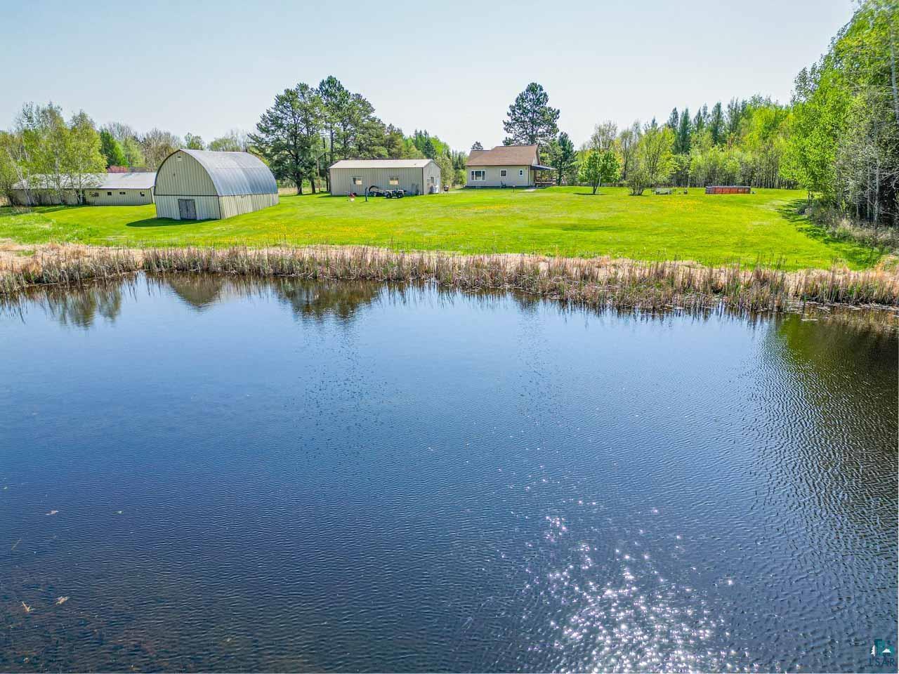2581 O'Rourke Road Hibbing, MN 55746 - Photo 46 of 61 Expansive property featuring a large pond with natural vegetation, extensive grassy areas, multiple outbuildings, and a single-story residence