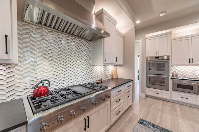 a kitchen with stainless steel appliances a stove a sink and cabinets