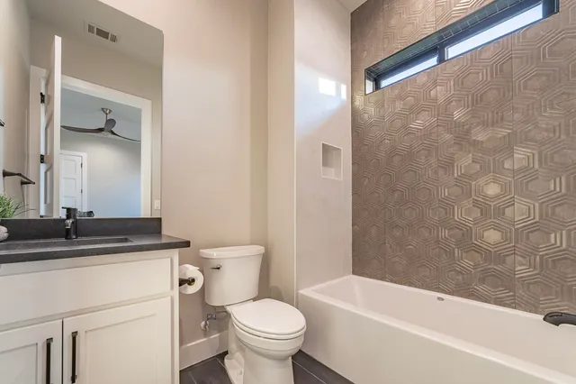 a bathroom with a granite countertop bathtub sink vanity mirror and toilet