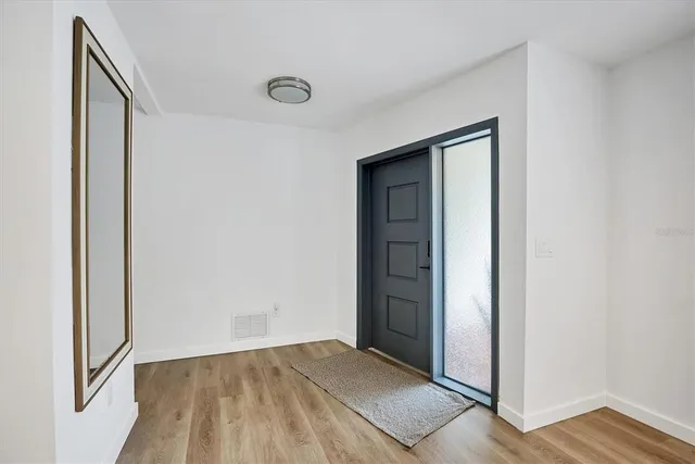 a view of an empty room with wooden floor and a window