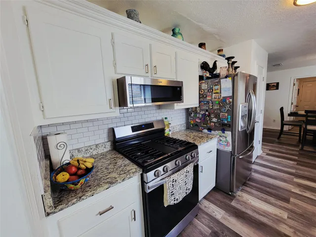 a kitchen with stainless steel appliances granite countertop a stove a sink and a refrigerator