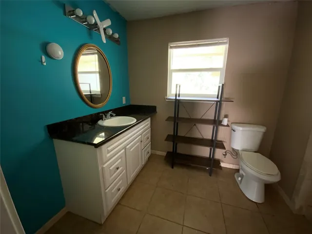 a bathroom with a toilet sink vanity and mirror