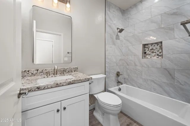 a bathroom with a granite countertop sink a toilet and bathtub