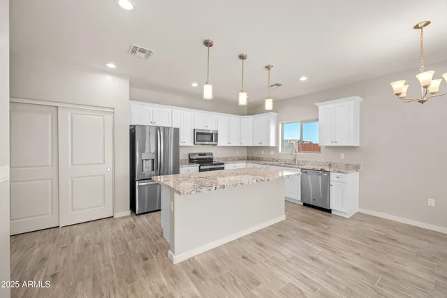 a kitchen with kitchen island white cabinets and stainless steel appliances