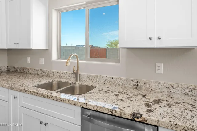 a kitchen with granite countertop white cabinets and a sink