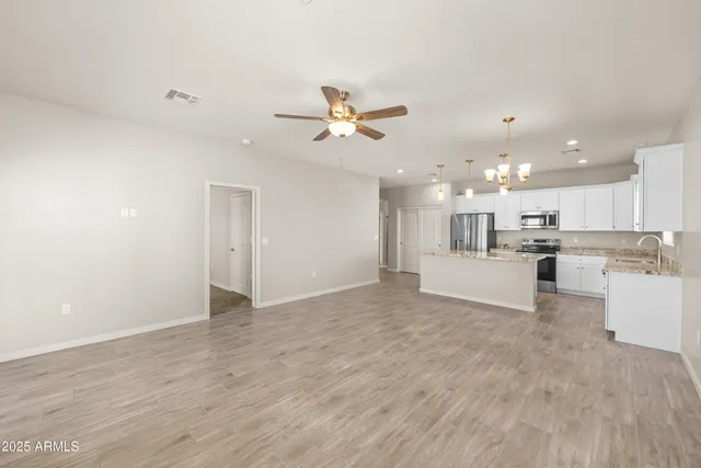 a view of a kitchen with kitchen island a sink stainless steel appliances and a chandelier