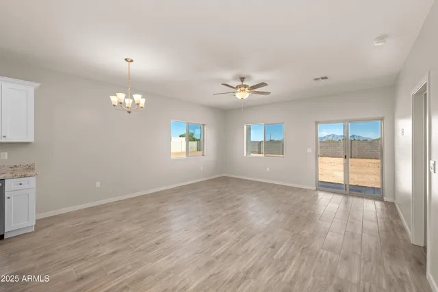 an empty room with chandelier fan and windows
