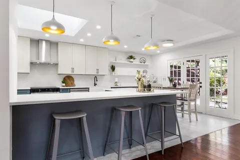 a kitchen with stainless steel appliances granite countertop a sink a stove a refrigerator and island with wooden floor