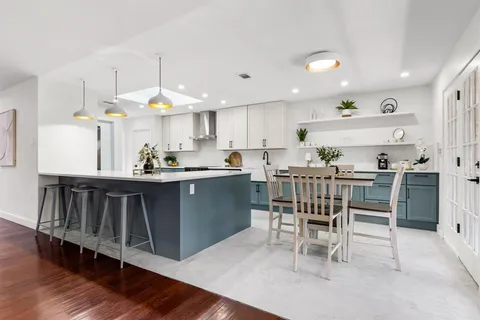 a kitchen with stainless steel appliances kitchen island granite countertop a table chairs sink and cabinets