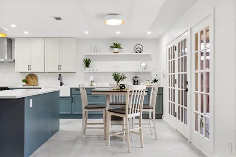 a kitchen with a dining table chairs refrigerator and cabinets