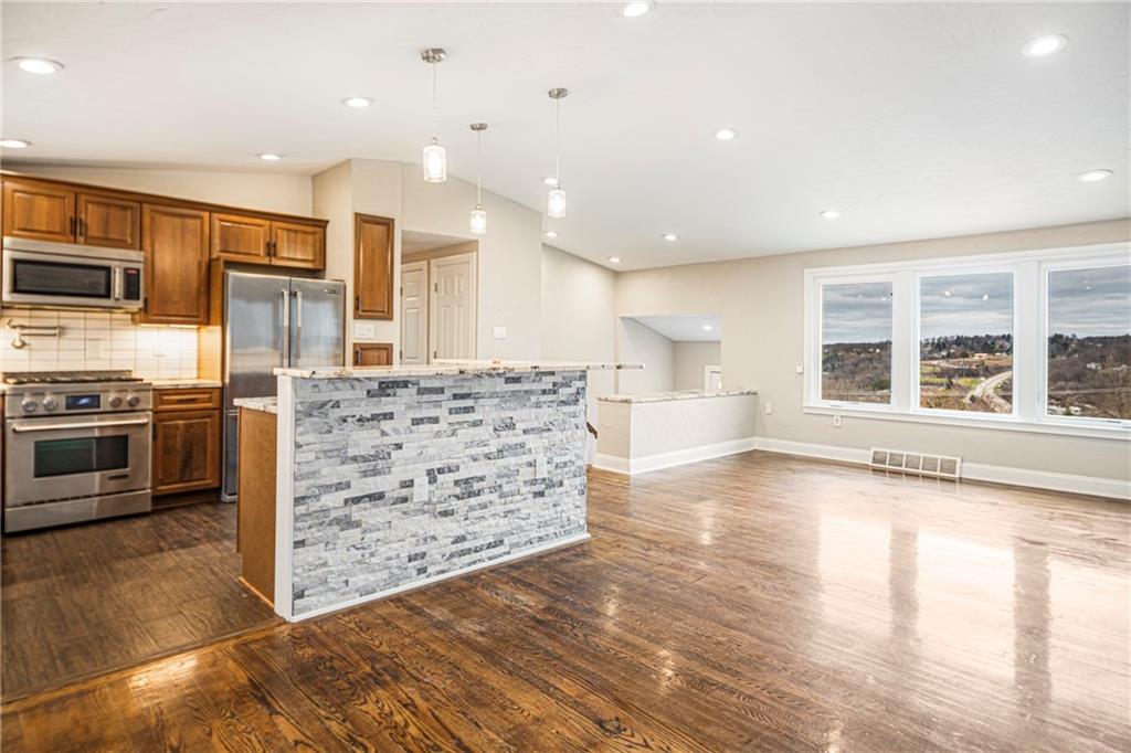 247 West Ingomar Road Pittsburgh, PA 15237 - Photo 5 of 36 a large kitchen with stainless steel appliances kitchen island granite countertop a large stove a refrigerator a sink and a large island with wooden floor