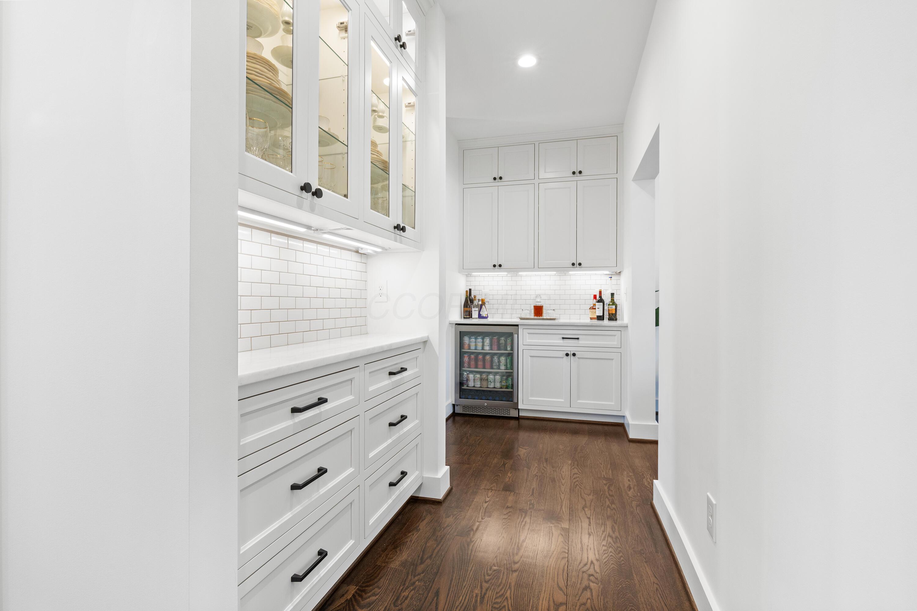 1364 Dale Ford Road Delaware, OH 43015 - Photo 16 of 112 • Hardwood flooring • White painted walls • Custom built wall cabinets • Custom built beverage center • Marble countertop • Ceramic tile backsplash • Soft-close drawers • Under cabinet lighting • Custom built china cabinet