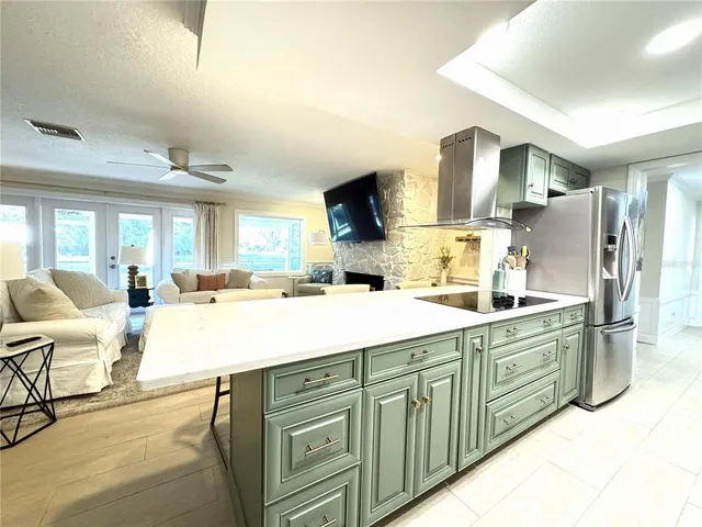 a kitchen with stainless steel appliances kitchen island granite countertop a refrigerator a stove and a sink with couches