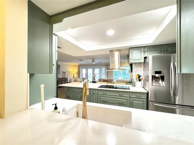 a large kitchen with stainless steel appliances a large counter top a stove and a refrigerator