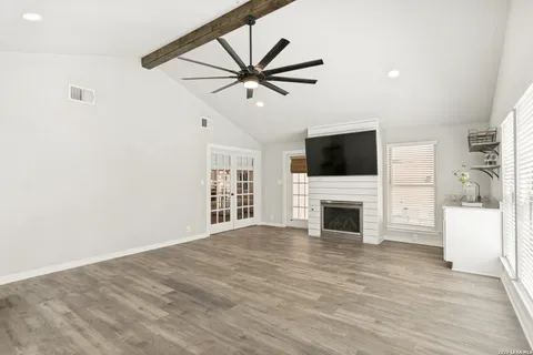 a view of a livingroom with a fireplace a ceiling fan and wooden floor
