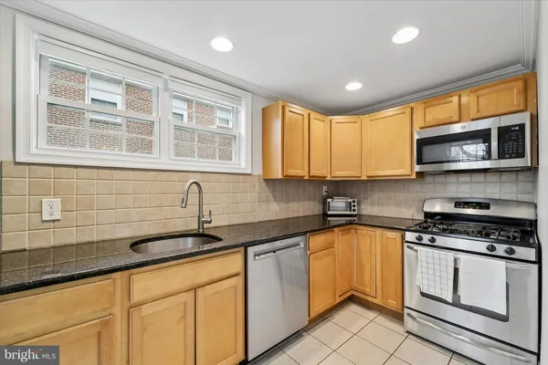 a kitchen with stainless steel appliances granite countertop a sink a stove a microwave a refrigerator and cabinets