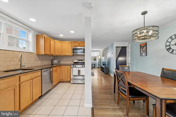 a kitchen with stainless steel appliances kitchen island granite countertop a sink a stove a dining table and chairs with wooden floor